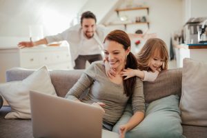 Family sitting on couch looking at computer.